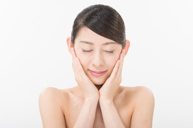 目を閉じて両手を頬に添える女性