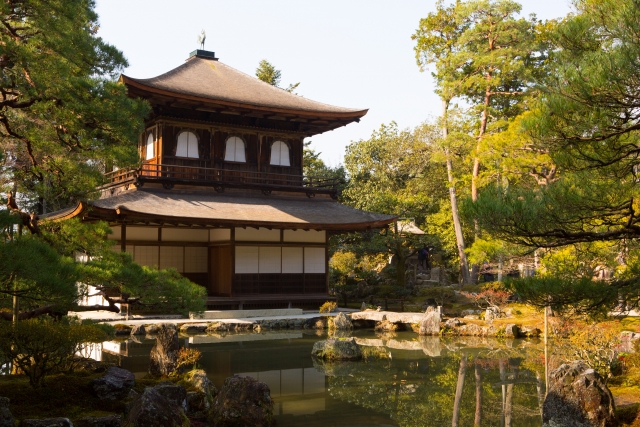 池と色づき始めた木々に囲まれた銀閣寺の風景