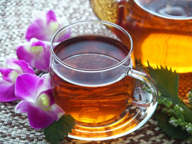 ガラスのカップに注いだお茶と紫の花