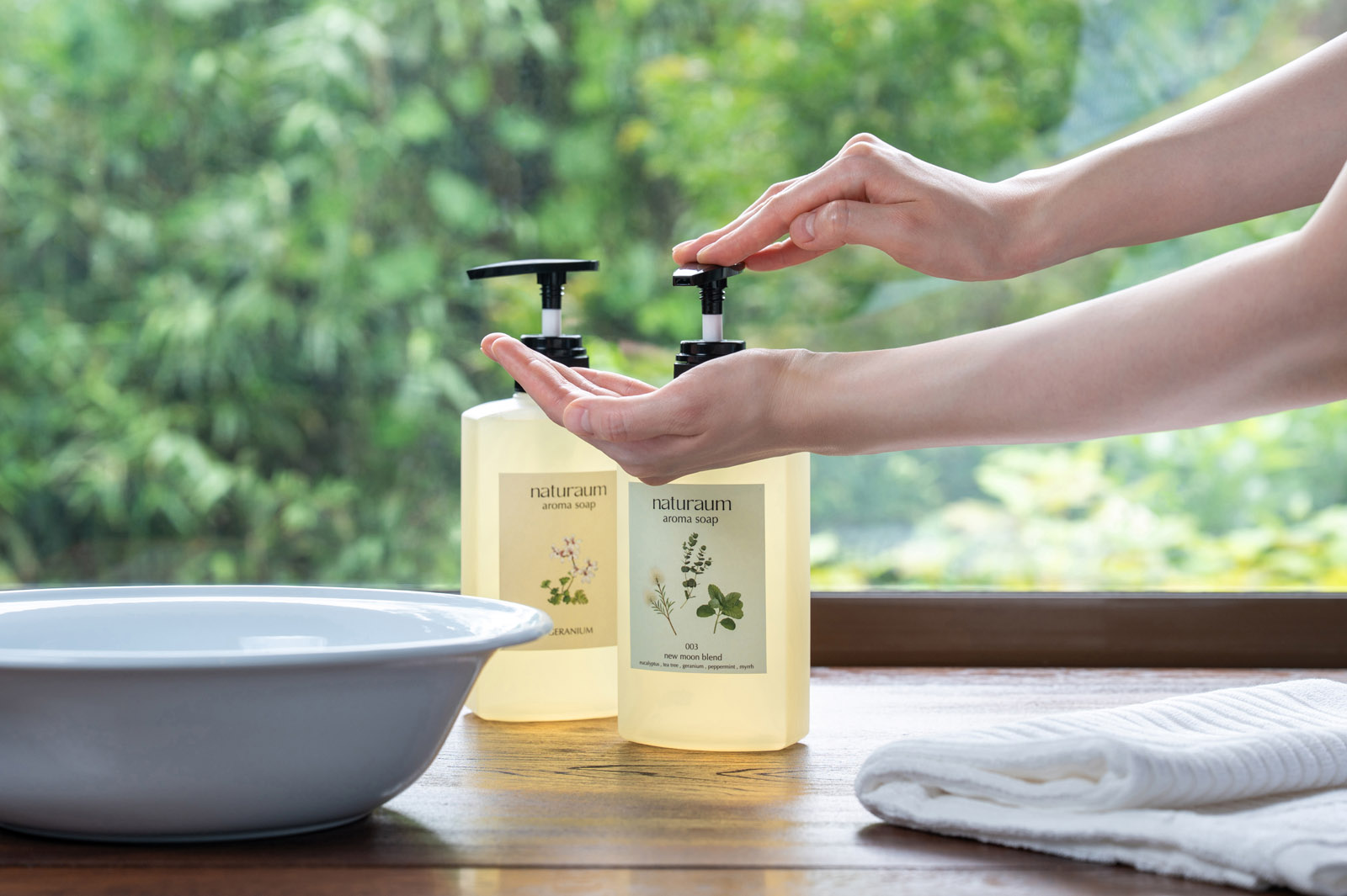 naturaumのアロマソープをポンプから手に取る場面と、洗面器とタオル