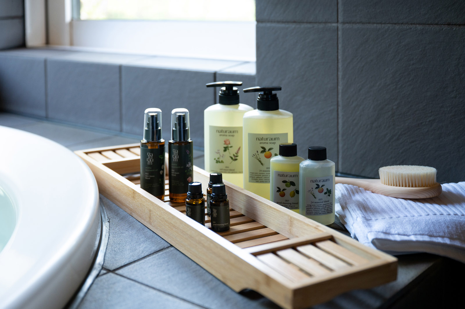 浴室の木製トレーに並べたポンプボトルとアロマ用品