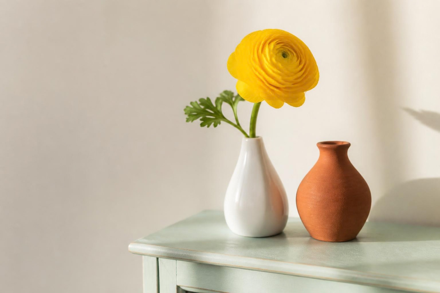 黄色い一輪の花を飾った白い花器と赤茶色の花器