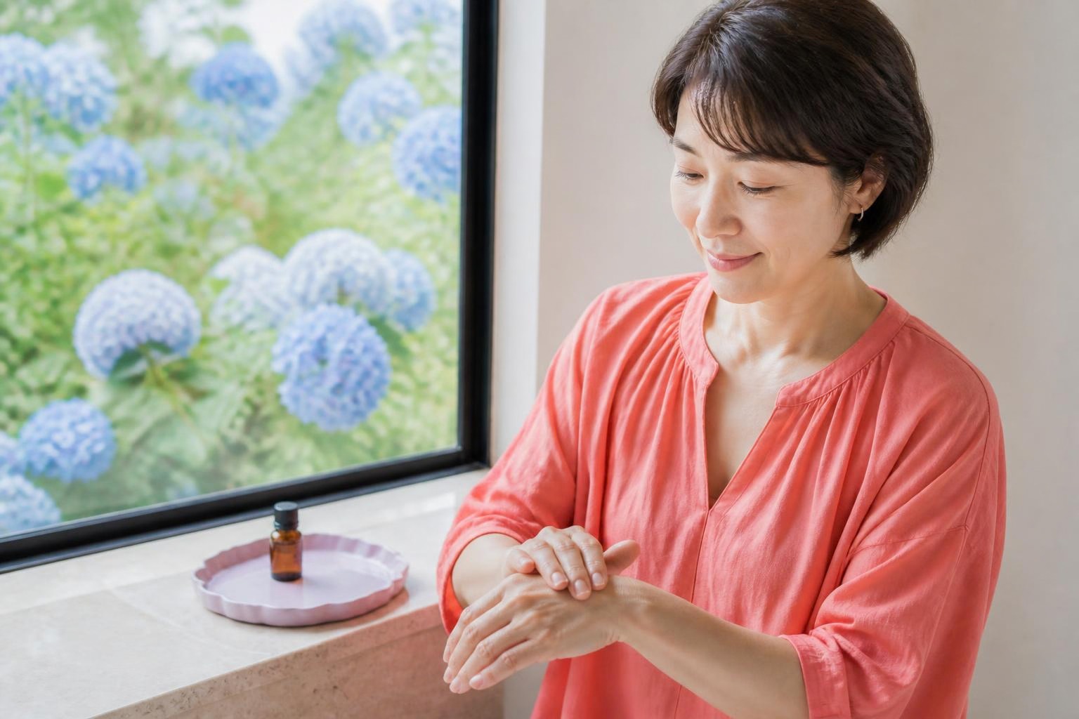 明るい窓辺で手の甲にオイルをなじませる女性