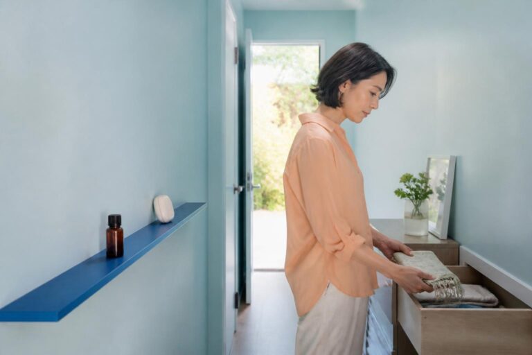 水色の朝の空間で身支度の道具を整える女性と棚のアロマストーン
