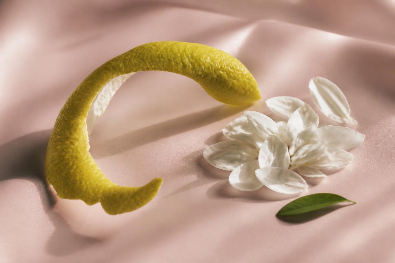 薄桃色の布に置いた柑橘の果皮と白い花びら