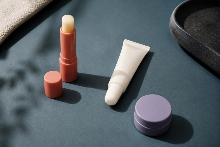 青緑の台に並べたスティック、チューブ、ジャーのリップケア容器