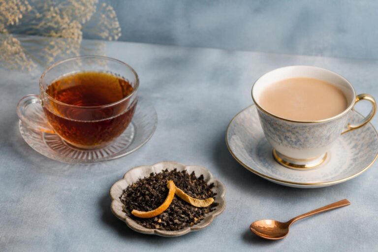 水色の背景に並べた紅茶とミルクティー、茶葉と柑橘の果皮